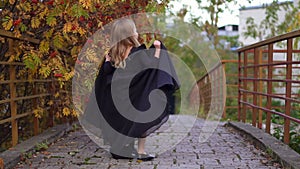 Happy laughing little girl on an autumn trail in a long black fashion dress. Halloween in a gorgeous princess dress