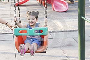 Happy laughing little girl enjoying on swing in playground