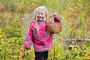 Happy laughing little girl is holding a wicker basket for picking wild berries