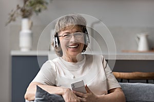 Happy laughing middle aged woman listening music in headphones.