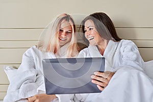 Happy laughing mother and teenage daughter with digital tablet