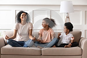 Happy laughing single black mom meditating with kids at home