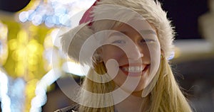 Happy laughing teenage girl or young woman in Santa hat outdoor on the Christmas eve.