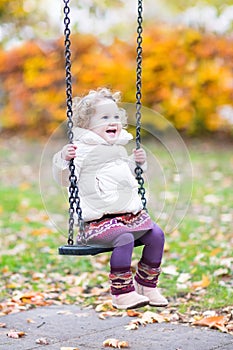 Happy laughing toddler girl playing on swing