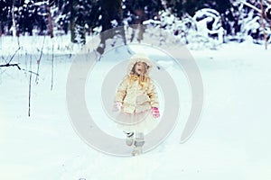 Toddler girl in fur coat walking in a snowy winter park