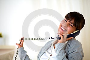 Happy laughing woman conversing on phone at home