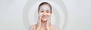 Happy laughing young asian woman washing face with foam soap cosmetic product. Web banner