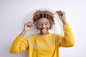 Happy laughing young frican woman with short curly hair on white background, touching hair and looking at side