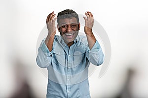 Happy laughing young man looking at camera standing on blurred background.