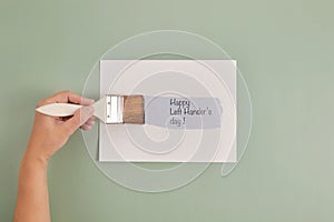 Happy Left Hander& x27;s Day. Left hand hold brush and writing text. photo
