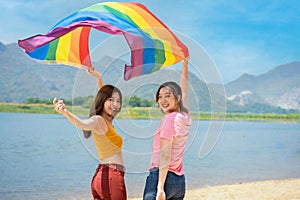 Happy lesbian, beautiful asian young two women, girl gay, couple love moment spending good time together, holding or waving lgbt