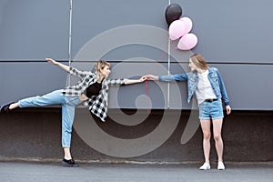 Happy lesbian couple holding hands with air balloons outdoors