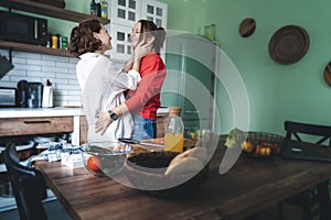 Happy lesbian couple hugging while standing in the kitchen at home. Cooking together, healthy eating