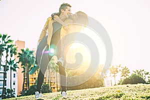 Happy lesbian couple piggyback having fun and laughing while looking each other eye in a park outdoor