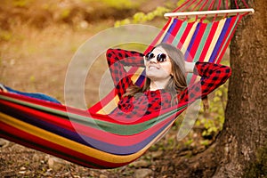Happy lifestyle concept. Beautiful carefree woman in sunglasses in forest being happy outdoors while rest on hammock