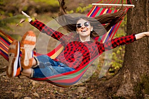 Happy lifestyle concept. Beautiful carefree woman in sunglasses in forest being happy outdoors while rest on hammock