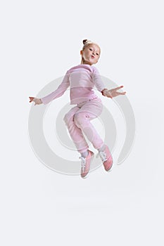 Happy little active Caucasian preschool girl jumping, having fun isolated over white background