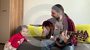 Happy little active infant cute baby dancing. Family playing guitar at cozy home. father teach little kid son boy to