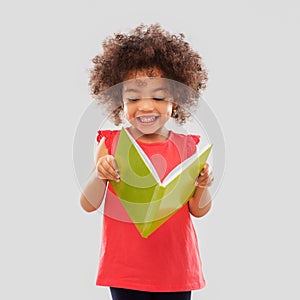 Happy little african american girl reading book