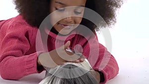 Happy little african curly girl is stroking fluffy Sheltie guinea pig at white background. Close up. Slow motion