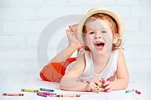 Happy little artist girl in a hat draws pencil