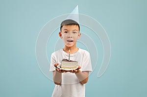 Happy Little Asian Boy In Party Hat Holding Birthday Cake With Candle