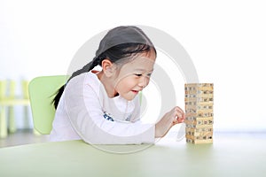 Happy little Asian child girl playing wood blocks tower game for Brain and Physical development skill in a classroom. Focus at