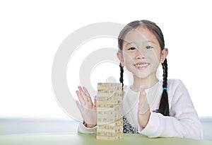 Happy little Asian child girl playing wood blocks tower game for Brain and Physical development skill in a classroom. Focus at