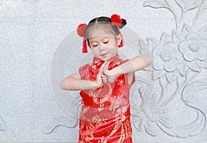 Happy little Asian child girl wearing red cheongsam with greeting gesture celebration for Chinese New Year at chinese temple in