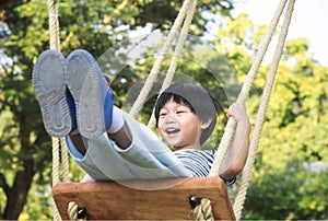 Happy little child laughing and swinging on a swing