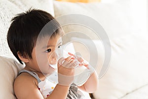 Happy little asian girl hand holding drinking milk glass