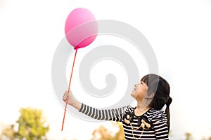 Happy Little asian girl holding pink balloon in hand selective focus.