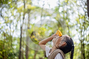 Happy Little Asian girls looking ahead and smiling child with the binoculars in the park. Travel and adventure concept. Freedom,