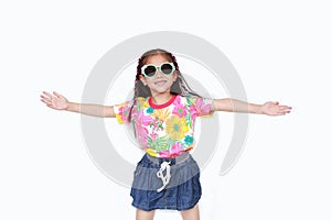 Happy little Asian kid girl stretch arms wide open wearing a floral pattern summer dress and sunglasses isolated on white