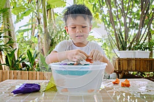 Happy little Asian school kid studying science, making A Boat Float Density Science Experiment with Modeling clay