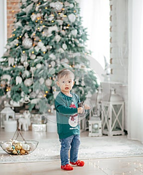 Happy little baby boy near Christmas tree with gifts