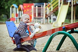 Happy little baby boy playing on the playground in the summer or autumn