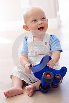 Happy little baby boy, toy and playing on floor in living room for fun childhood or development at home. Face of cute or