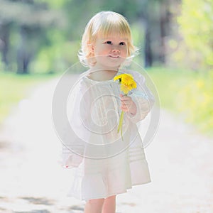 Happy little baby girl with yellow dandelion