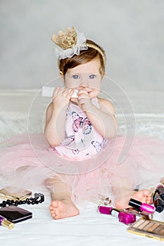 Happy little baby playing with her mother`s cosmetics