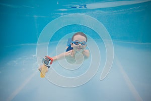 Happy little baby swims underwater in the pool with action camera . Shooting under water. Landscape orientation