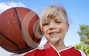 Happy little basketball player. A cute little girl holding a basketball and smiling at the camera.