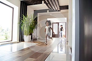 Excited american kid running in hallway entering big modern house