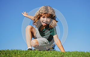 Happy little blond child laying on the grass in the park. Smmer day during school holidays. Amazed kid boy dreaming and