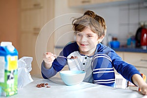 Happy little blond kid boy eating cereals for breakfast or lunch. Healthy eating for children. Child in colorful pajama