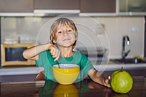 Happy little blond kid boy eating cereals for breakfast or lunch. Healthy eating for children. Child having breakfast