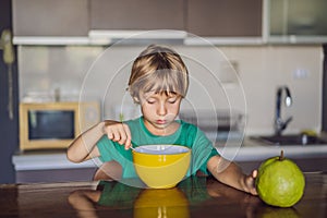 Happy little blond kid boy eating cereals for breakfast or lunch. Healthy eating for children. Child having breakfast