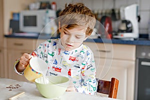 Happy little blond kid boy eating cereals for breakfast or lunch. Healthy eating for children in the morning. Child in