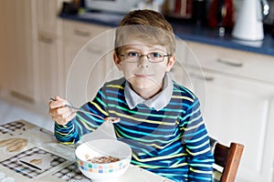 Happy little blond kid boy eating cereals for breakfast or lunch. Healthy eating for children.