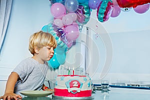 Happy little boy blow candles on the birthday cake party